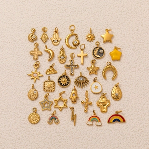 Close-up of assorted gold charms with celestial symbols, rainbow, and rhinestones