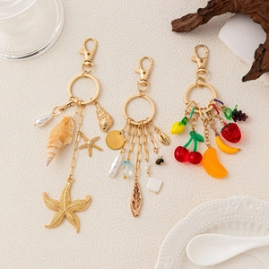 Detail of 14K gold plated DIY keychain charms with starfish, shells and colorful fruit pendants