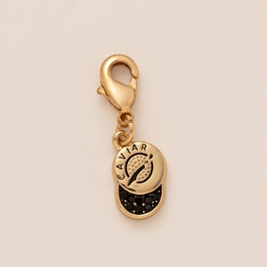 Detailed view of golden lobster clasp pendant with black caviar style beads and metal tag