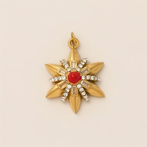 Detalle de colgante de estrella con piedra roja central y circonitas en oro