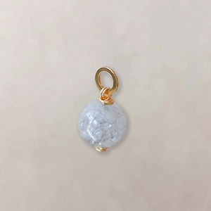 Detail van een lichtblauwe ovale stenen hanger met gouden draadwikkeling