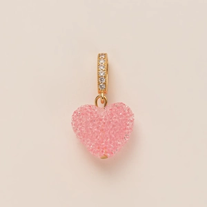 Macro view of a heart-shaped pink crystal pendant with a gold zircon-set bail