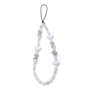 Detail of beaded phone strap with white heart and silver dice charms on plain background