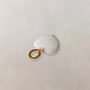 Detailopname van hartvormige roomwitte jade hanger met een gepolijste gouden metalen lus