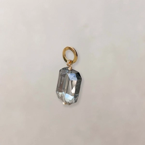 Close-up van de grijs kristallen hanger in smaragd slijpvorm met gouden ringetje