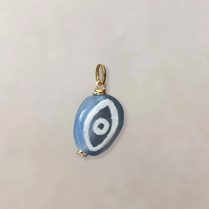Detail van blauwe ovale agaat hanger met boze oog patroon en gouden draadwikkel