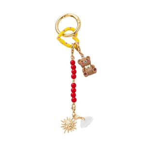 DIY charm keychain with brown bear, golden sun mask, and red beads on a white background