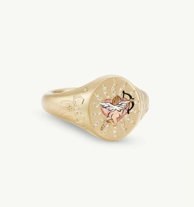 Macro detail of Cupid heart ring featuring gold bow engravings and matte metal texture