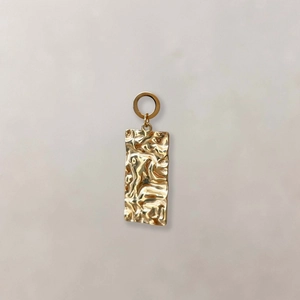 Detail van een gouden rechthoekige hanger met gehamerde textuur en vintage reflecties