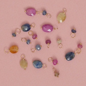 Gefacetteerde natuursteen hangers met gouden metalen ringen op roze achtergrond