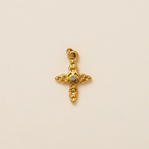 Detalle del colgante de cruz calada en oro de 18K con una piedra de circón central