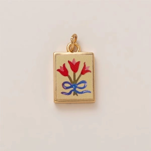 Detail of a rectangular gold-edged pendant featuring a pink tulip and blue ribbon bow
