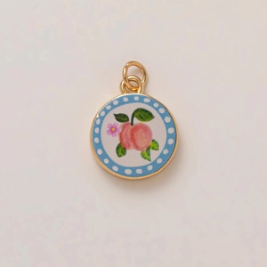 Detail of round peach pendant with sky blue polka dot border and gold-plated finish