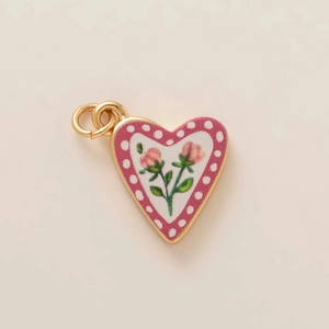 Close-up of heart-shaped gold pendant with pink roses and white polka dot border