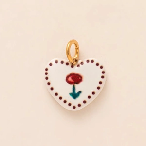 Close-up of heart-shaped ceramic pendant with hand-painted red flower and gold jump ring