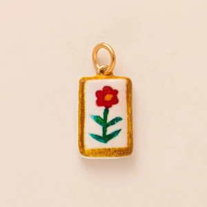 Detail of rectangular white enamel pendant with red flower and gold metal ring