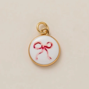 Vue détaillée du pendentif rond doré avec un motif de nœud rose sur fond blanc