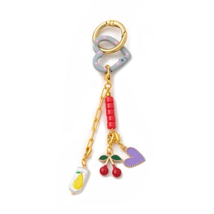 Détail du porte-clés plaqué or 18K avec breloques cœur et fruits sur fond blanc épuré