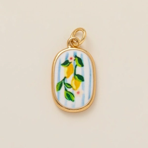 Detailed close-up of oval lemon pendant with yellow metal frame and blue striped background