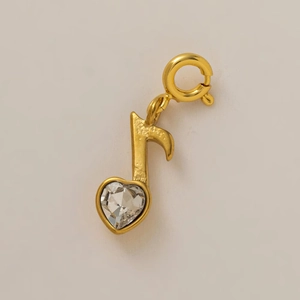 Détail macro d'un pendentif note de musique dorée avec un cristal en forme de cœur