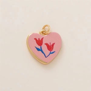 Dettaglio di un ciondolo a cuore con rivestimento rosa e motivi floreali di tulipani
