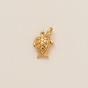 Detailed close-up of a golden sea turtle pendant with intricate grid pattern shell