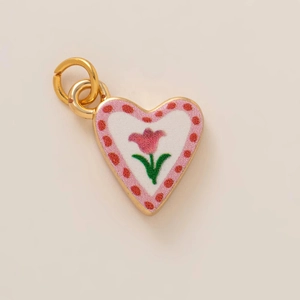 Macro shot of heart pendant with pink tulip and red dots on creamy enamel finish