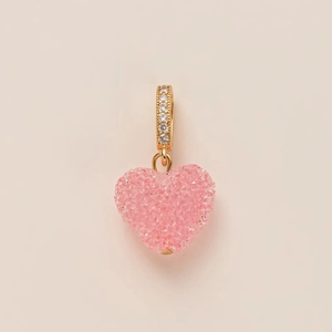 Dettaglio macro di un ciondolo a cuore rosa placcato oro con zirconi brillanti incastonati