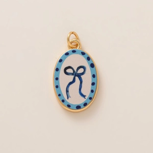 Dettaglio del ciondolo ovale in ceramica con bordo dorato e fiocco blu dipinto a mano