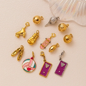 Assorted 18K gold and silver plated stainless steel sports themed pendants on beige surface