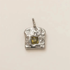 Macro view of toast bread pendant with hammered texture and yellow square gemstone