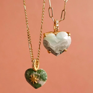 Macro detail van 18K gouden hart hangers met groene steen en gefacetteerde agaat textuur