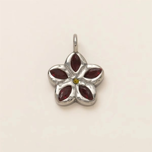 Macro shot of silver floral pendant with red marquise stones and yellow center gem