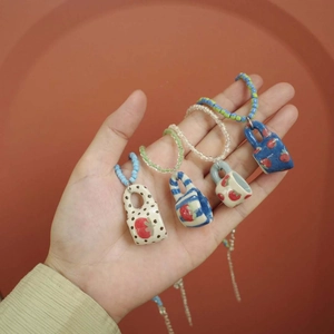 Detailed view of handmade ceramic strawberry pendants with colorful beaded lanyards