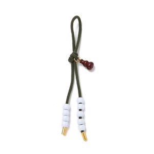 Detail of green braided rope keychain with wooden gourd charm and white decorative beads