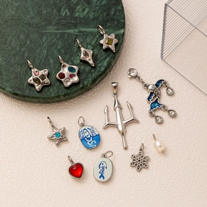 Various stainless steel 18K gold star and snowflake charms on a beige background
