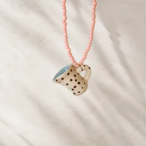 Detailed view of pink beaded necklace with creative polka dot coffee cup pendant