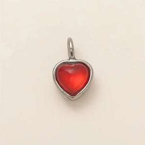 Detailed view of heart-shaped pendant with red resin stone and silver metal frame