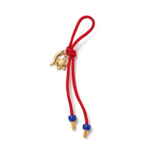 Détail d'un bijou de sac en corde tressée rouge avec pendentifs étoile et piment dorés