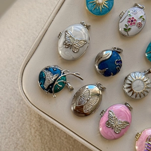 Detail showing vintage locket pendants with enamel butterflies and celestial sun motifs