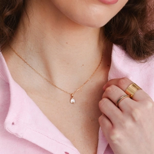 Detailed view of an 18K gold moonstone necklace paired with elegant stacked gold rings