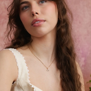 Close-up of a gold-plated heart pendant necklace with zircons on a model's neck