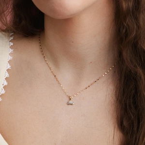 Detail of gold butterfly pendant with blue sapphire and white zircon on fine chain