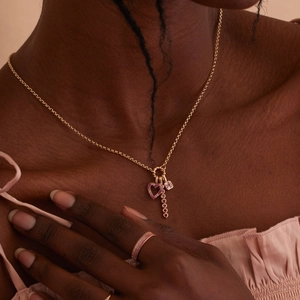 Close-up of gold heart necklace and matching ring with pink cubic zirconia stones