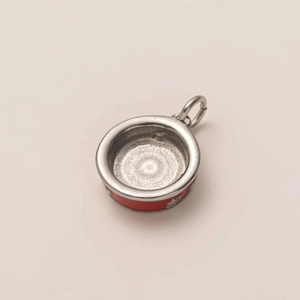Dettaglio macro di un ciondolo tondo in acciaio inox con smalto rosso e motivo a stelle