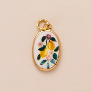 Detail of oval golden charm with enamel lemon and flower pattern for jewelry making