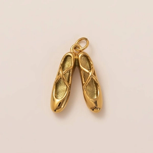 Detailed close-up of golden ballet shoe pendants with fine polished 18K gold finish