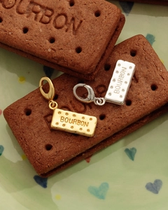Dettaglio dei ciondoli a forma di biscotto Bourbon in oro e argento con moschettoni