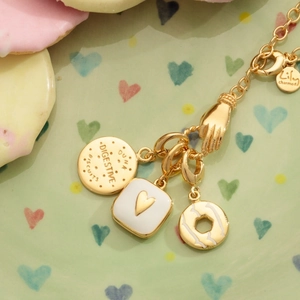 Bracciale placcato oro con ciondoli a forma di biscotto e cuore su un piatto decorativo