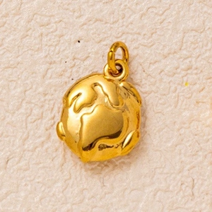 Macro shot of 18K gold plated globe pendant with detailed 3D relief on warm texture